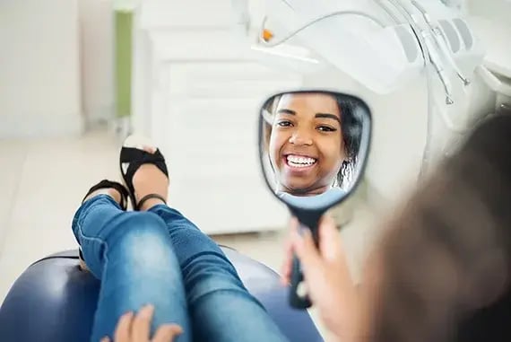 happy-female-patient-looking-in-mirror-570x381